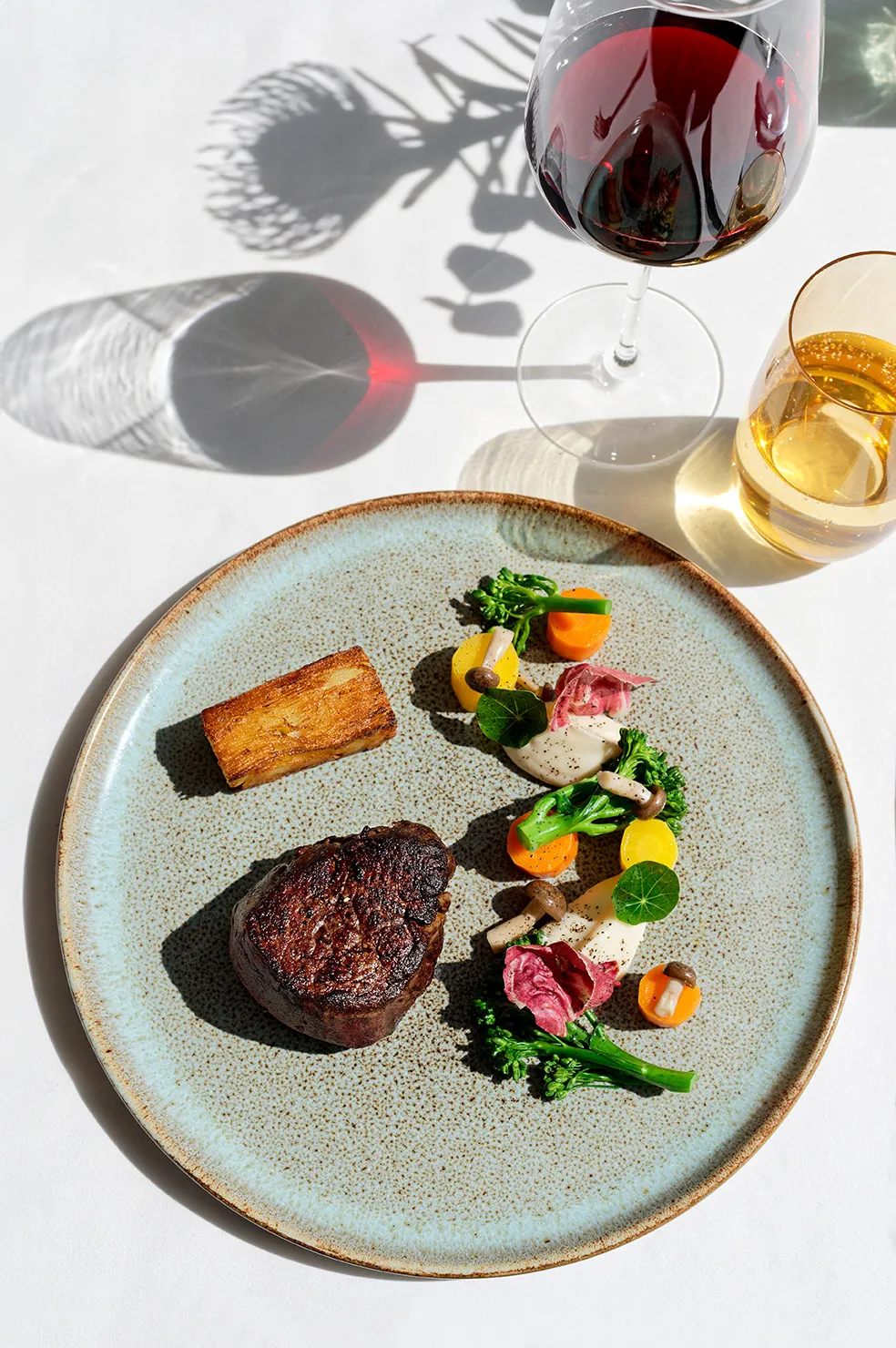 Black Angus Rinderfilet angerichtet als Tellergericht mit saisonalem Gemüse und einem Glas Rotwein