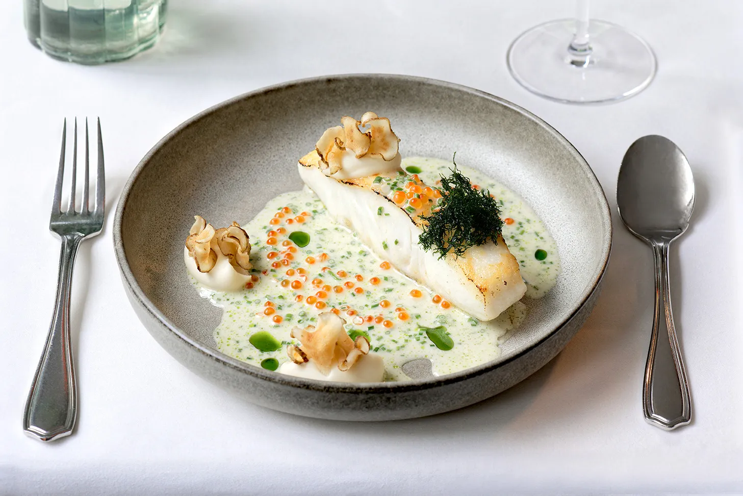 Fischgericht, weißer Heilbutt, angerichtet auf einem Teller mit gedecktem Tisch