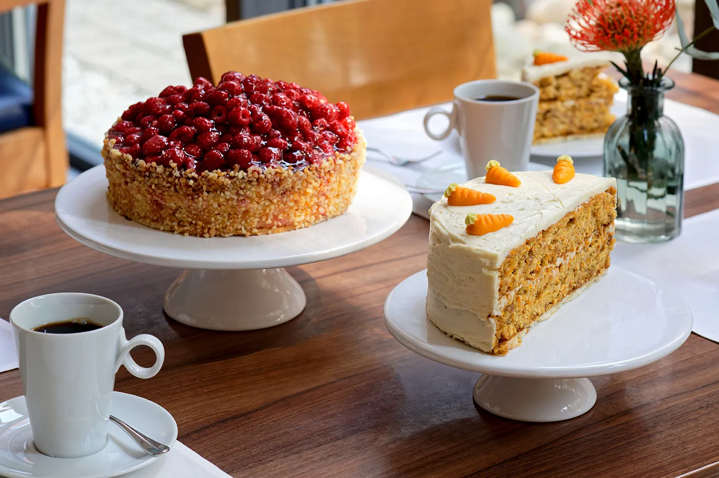 Kuchenzeit: Rüblitorte und Beerenkuchen mit 2 Tassen Filterkaffee auf einem angerichteten Tisch zur Kaffeezeit