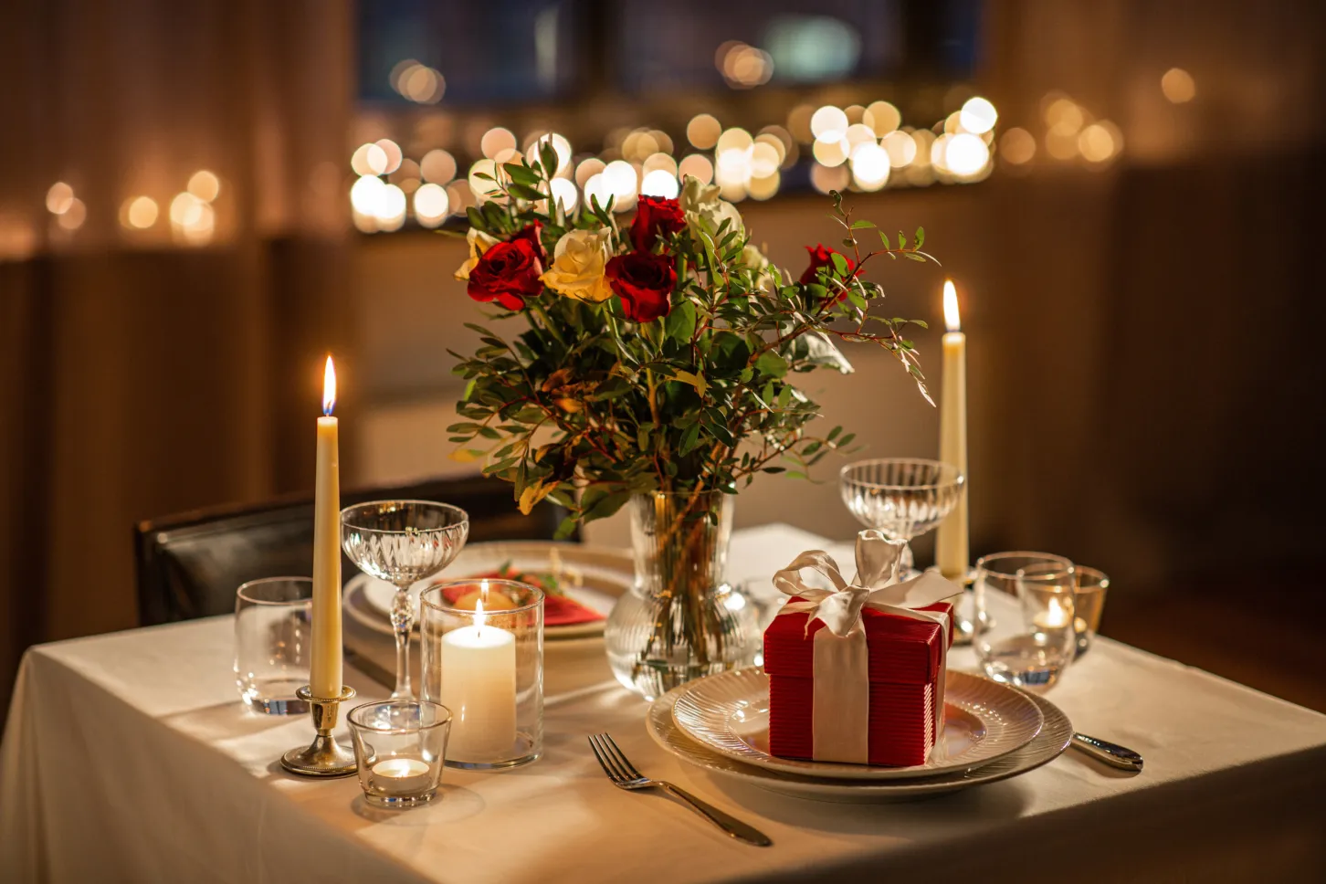 Gedeckter Tisch zum Valentinstag mit Kerzen und Rosen