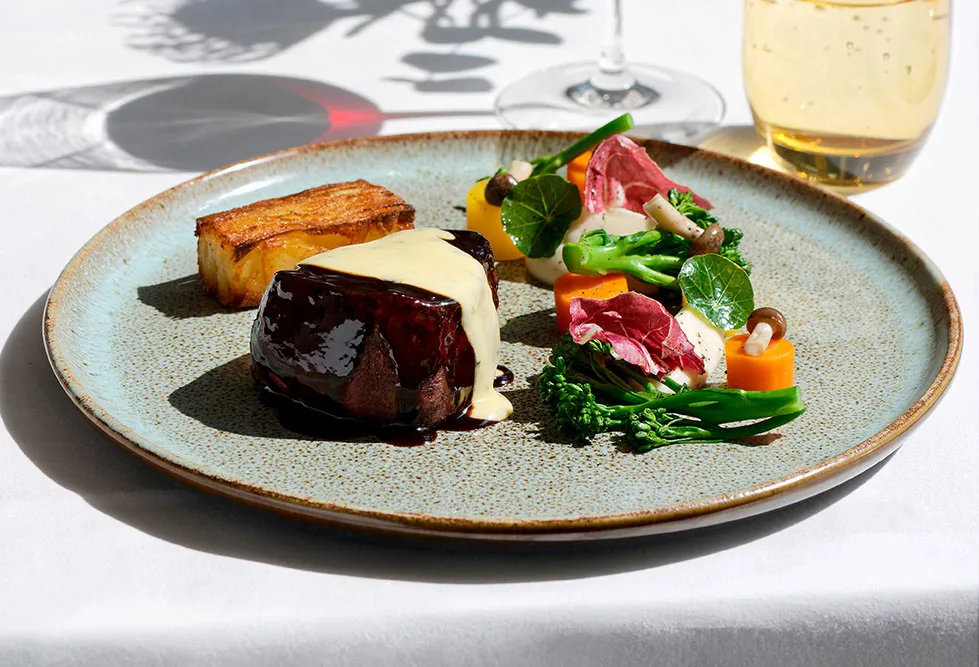 Black Angus Rinderfilet angerichtet als Tellergericht mit saisonalem Gemüse und einem Glas Rotwein